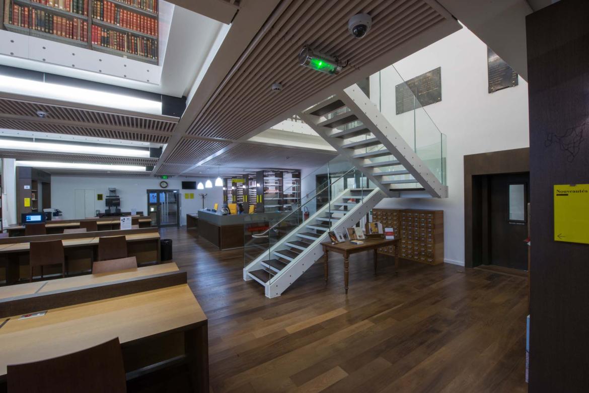 Vue du niveau 0 de la bibliothèque, tables de la salle de lecture et escalier
